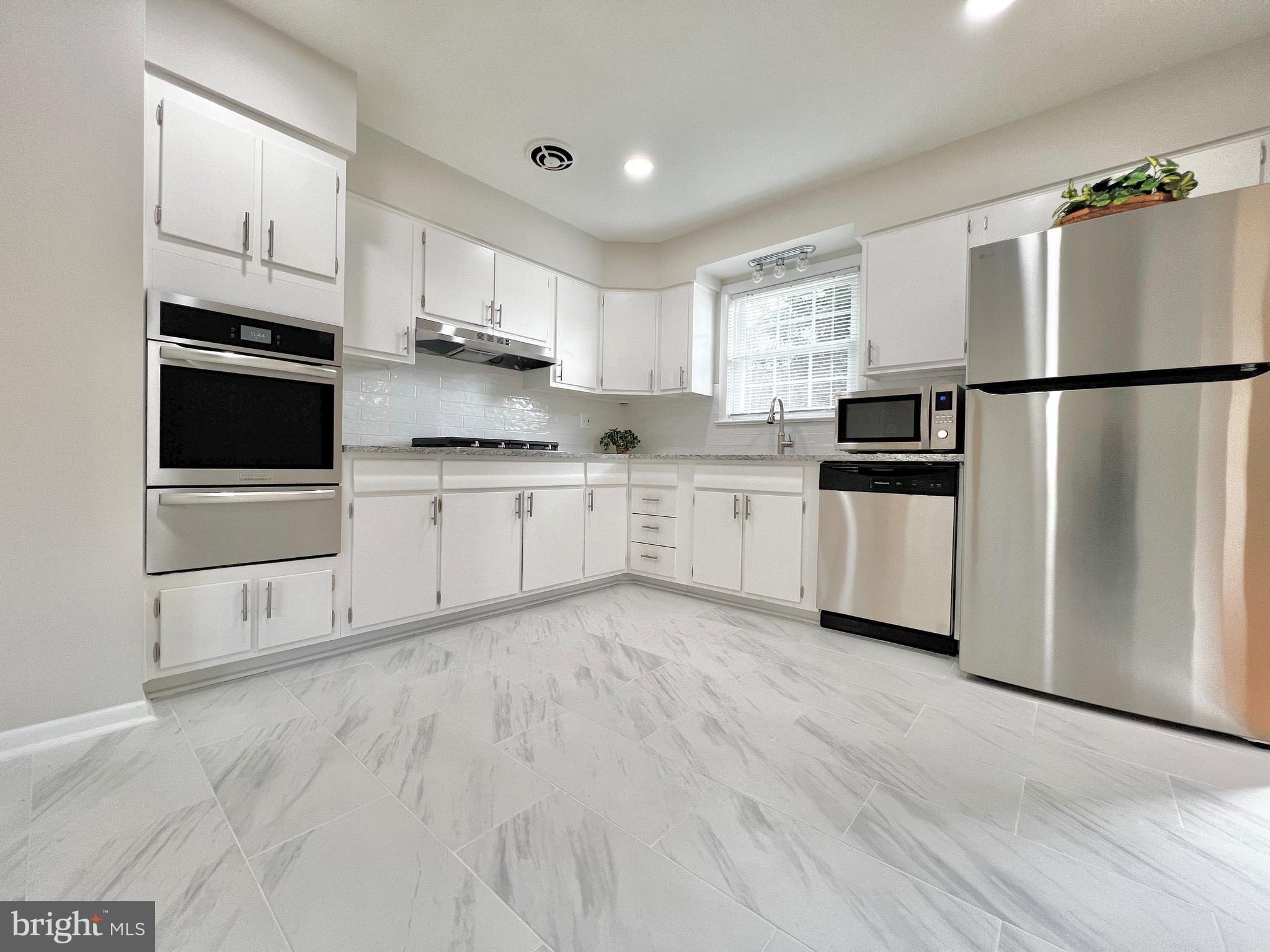11218 Keystone Avenue Clinton, MD 20735 - Photo 13 of 53 a kitchen with white cabinets and stainless steel appliances