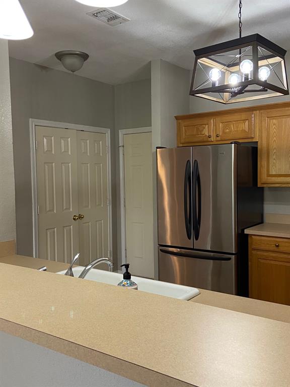 27101 Meadowmore Court Whitney, TX 76692 - Photo 9 of 31 a kitchen with a refrigerator and a chandelier