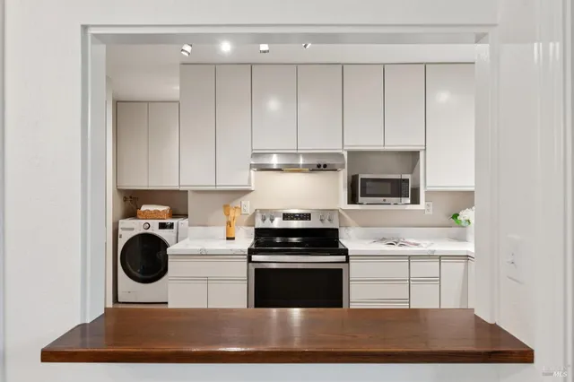 a kitchen with kitchen island granite countertop stainless steel appliances a stove a sink a refrigerator and cabinets