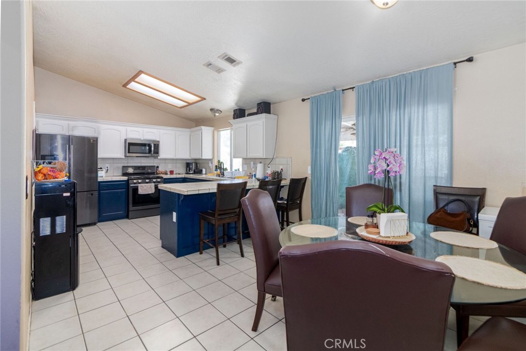 18936 Rock Springs Road Hesperia, CA 92345 - Photo 7 of 28 a living room with stainless steel appliances kitchen island granite countertop a dining table chairs and a refrigerator