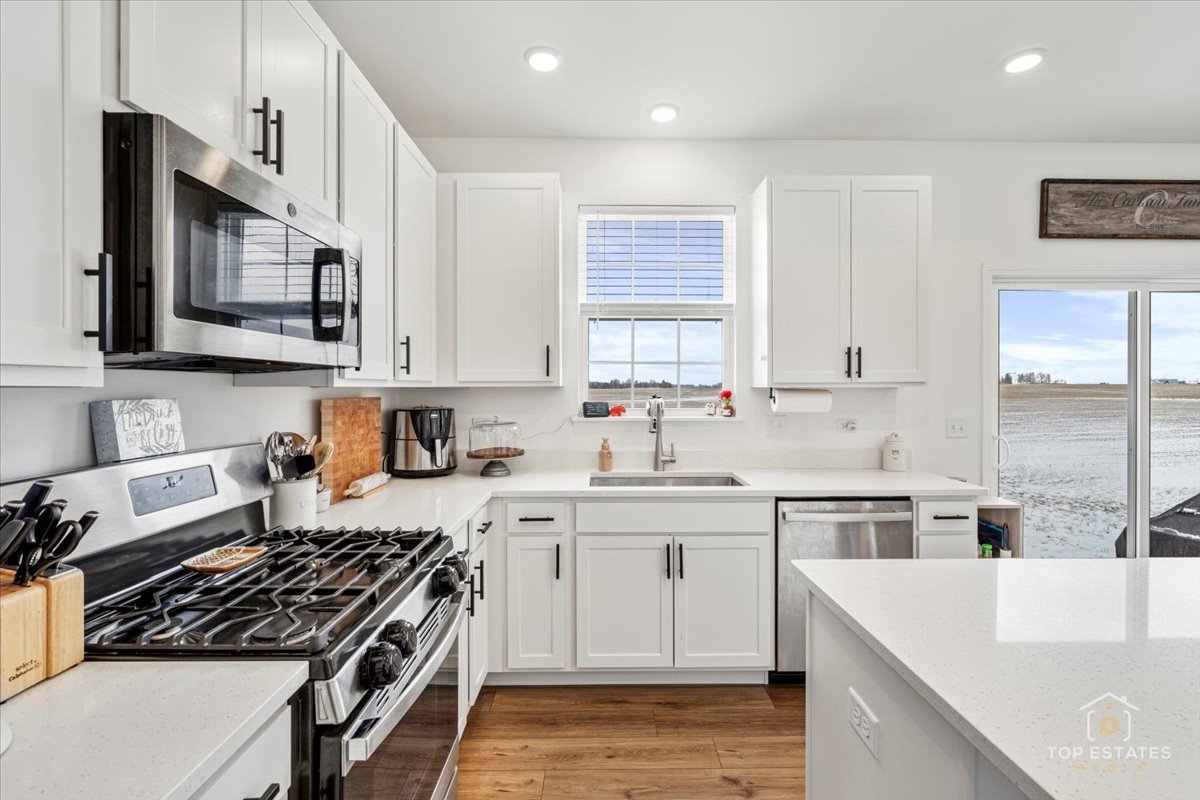 1457 Collins Street Elburn, IL 60119 - Photo 11 of 39 a kitchen with stainless steel appliances granite countertop a stove a sink dishwasher and white cabinets with wooden floor