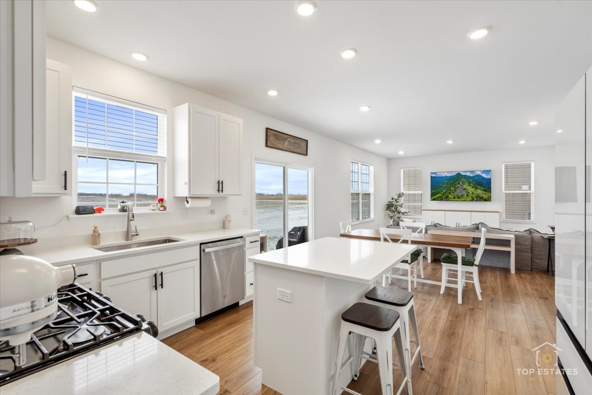 1457 Collins Street Elburn, IL 60119 - Photo 10 of 39 a large kitchen with kitchen island a island a sink a stove and wooden floors
