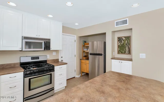 a kitchen with kitchen island granite countertop wooden cabinets and refrigerator