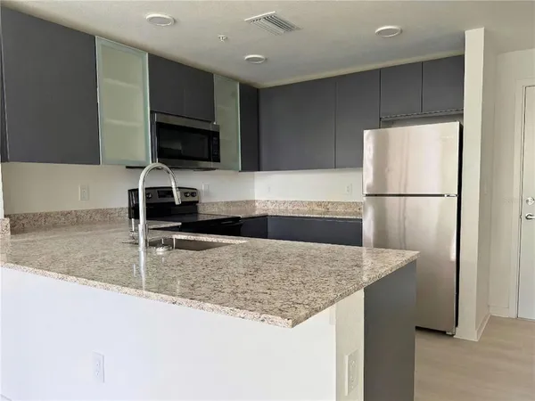 a kitchen with stainless steel appliances granite countertop a sink refrigerator and microwave