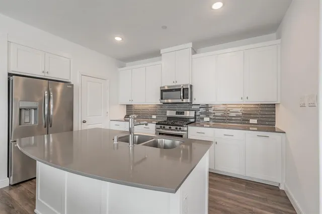 a kitchen with granite countertop cabinets stainless steel appliances and wooden floor