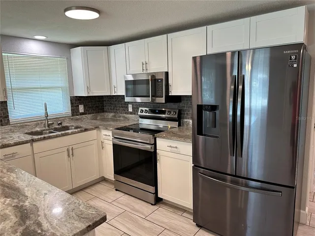 a kitchen with granite countertop a refrigerator and a sink