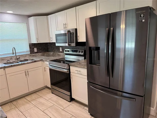 a kitchen with granite countertop a sink stove and cabinets