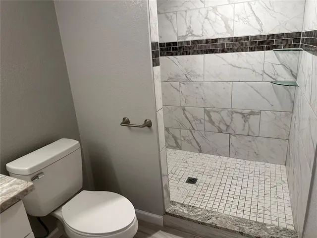 a bathroom with a granite countertop sink mirror vanity and toilet