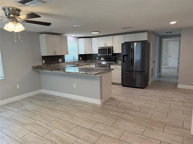 a kitchen with granite countertop a refrigerator a sink a stove a microwave and cabinets