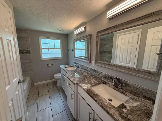 a view of a house with a yard and large tree
