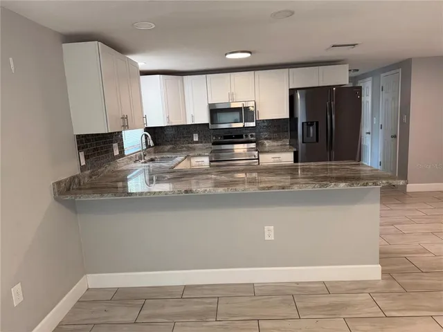 a kitchen with stainless steel appliances granite countertop a refrigerator stove a sink and a granite counter tops