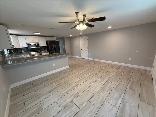 a kitchen with stainless steel appliances white cabinets white and wooden floors