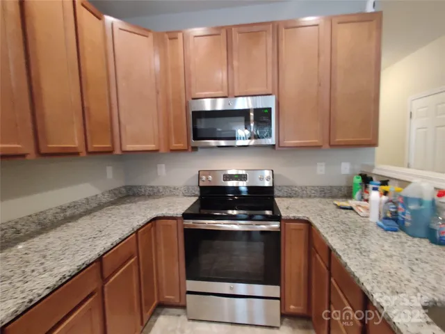 a kitchen with granite countertop a stove top oven microwave and cabinets