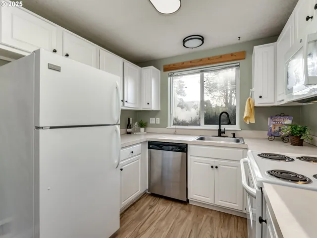 a kitchen with a refrigerator a sink and white cabinets
