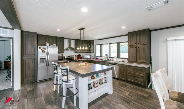 a kitchen with stainless steel appliances granite countertop a refrigerator a sink dishwasher a stove and white countertops with wooden floor