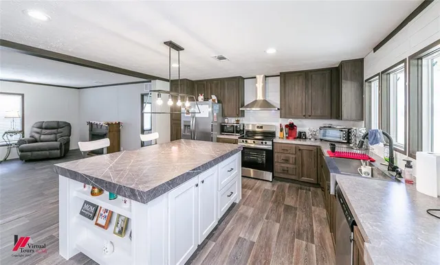a kitchen with kitchen island granite countertop a sink appliances and cabinets