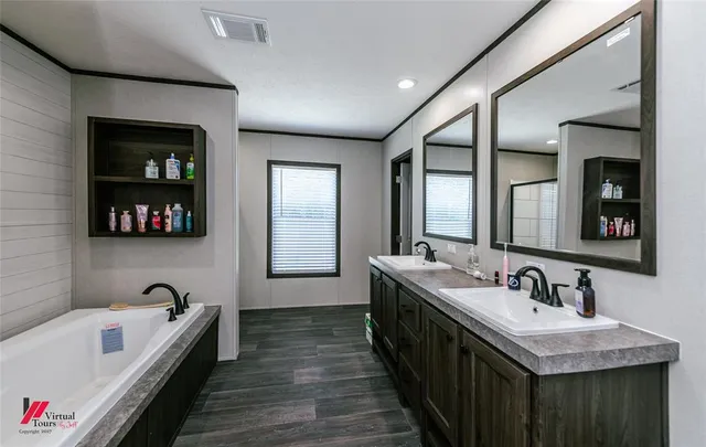 a bathroom with a bathtub a double vanity sink and a mirror