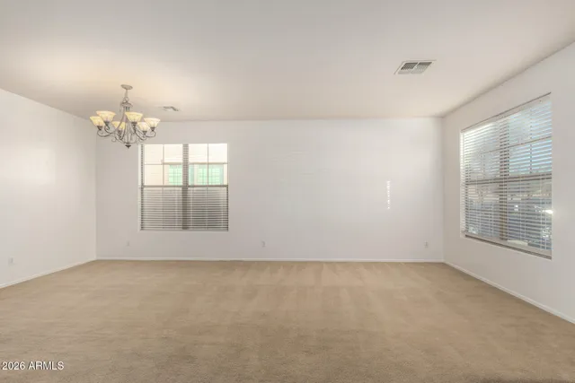 an empty room with chandelier fan and windows