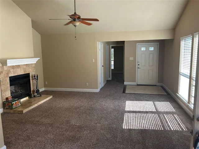 a view of a livingroom with a fireplace a ceiling fan and windows