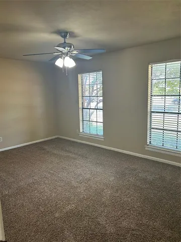an empty room with windows and chandelier fan