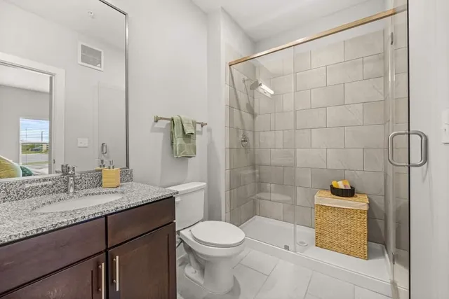 a bathroom with a granite countertop sink a toilet and shower