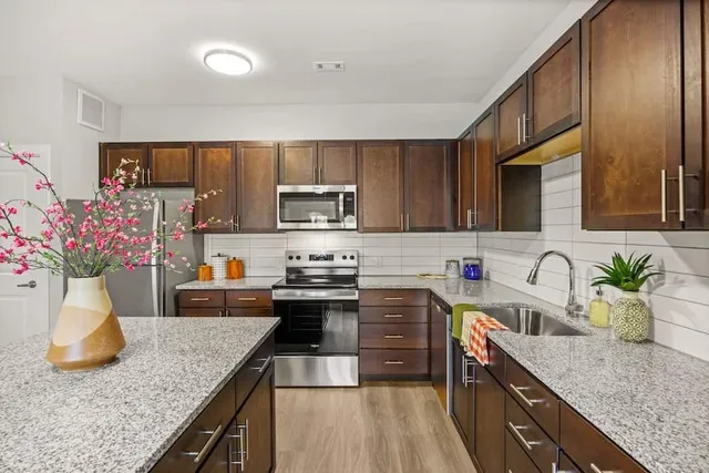 a kitchen with granite countertop a sink a counter top space appliances and cabinets