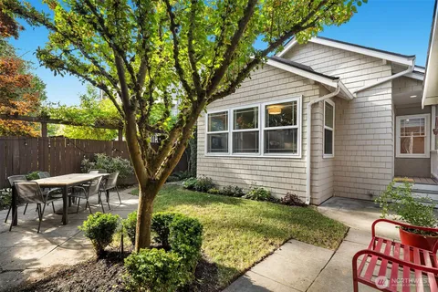 a view of a backyard with table and chairs potted plants and large tree