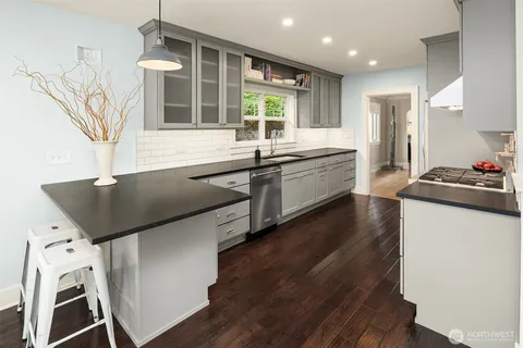 a kitchen with stainless steel appliances granite countertop a refrigerator a sink dishwasher a stove and white countertops with wooden floor