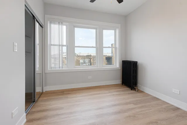 a view of empty room with wooden floor and fan