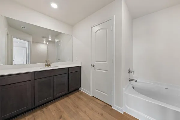 a bathroom with a tub sink and mirror