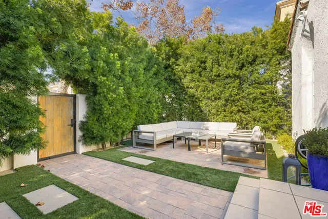 a view of a patio with table and chairs potted plants and large tree