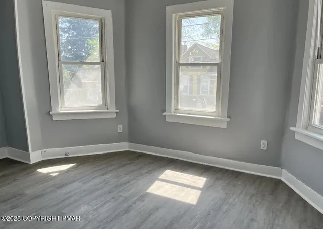 a view of an empty room with wooden floor and a window