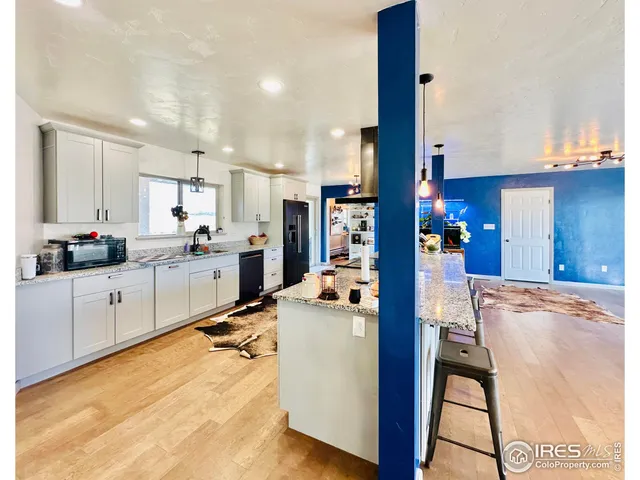 a view of a dining room kitchen with stainless steel appliances kitchen island granite countertop a table chairs and a living room