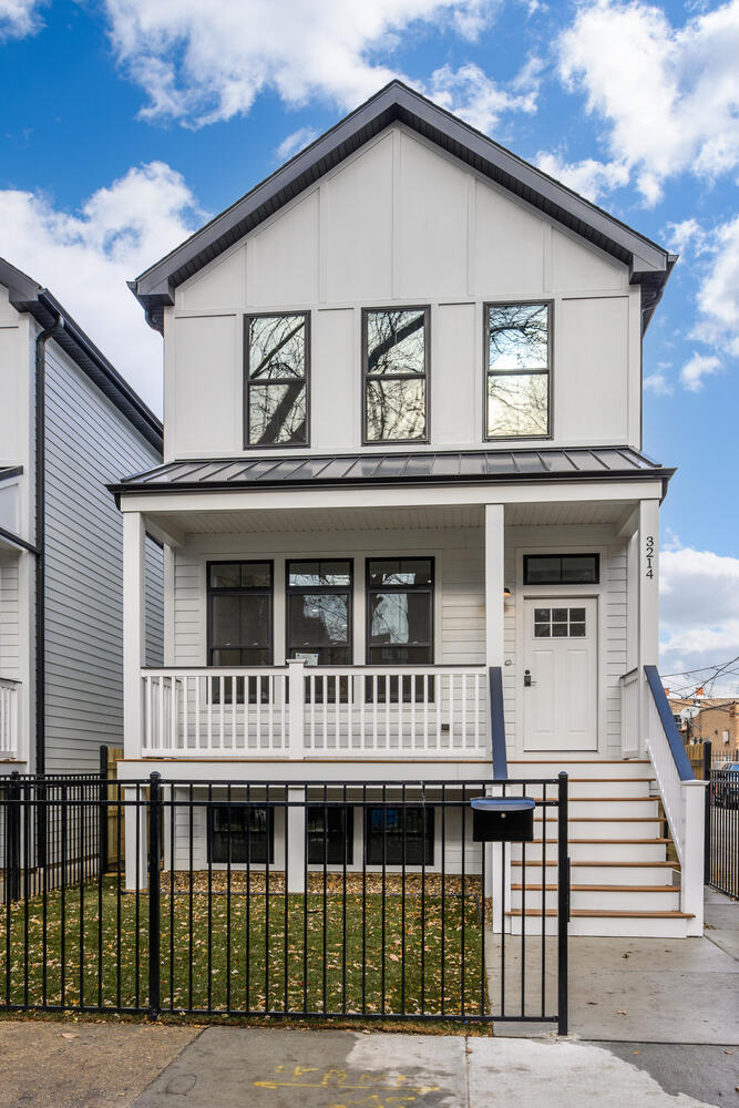 a view of a white house with large windows and a small yard