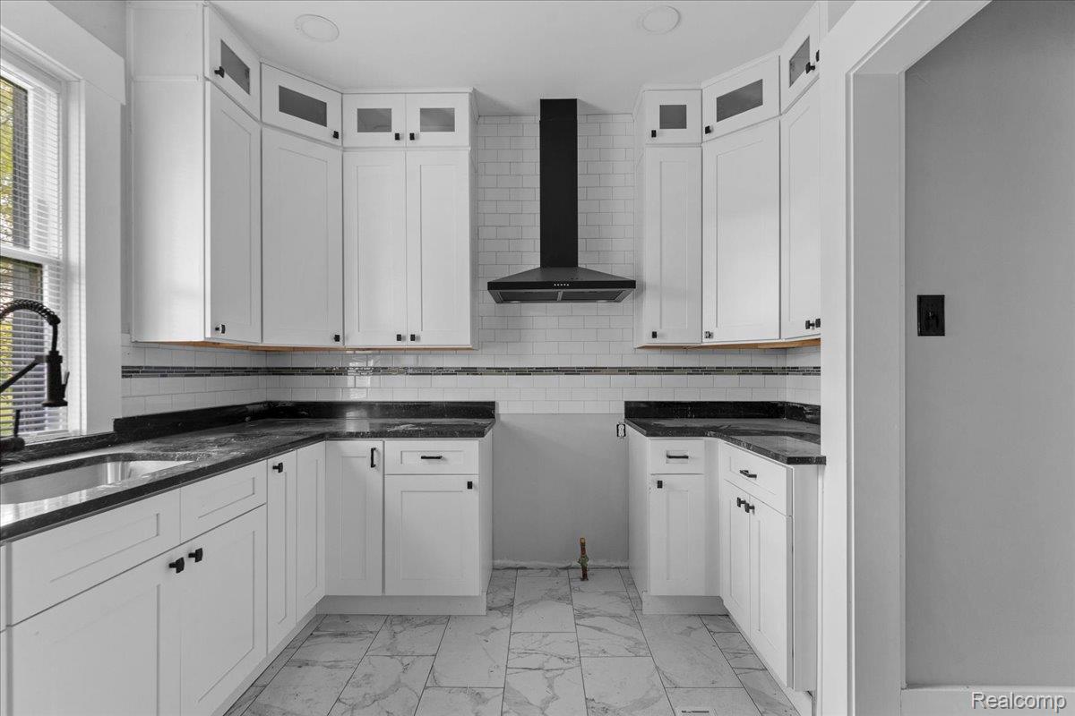 58 East Philadelphia Street Detroit, MI 48202 - Photo 11 of 24 Modern kitchen featuring white shaker cabinetry with dark hardware, dark countertops, a stainless steel sink with a dark faucet, white subway tile backsplash, and light-toned tile flooring