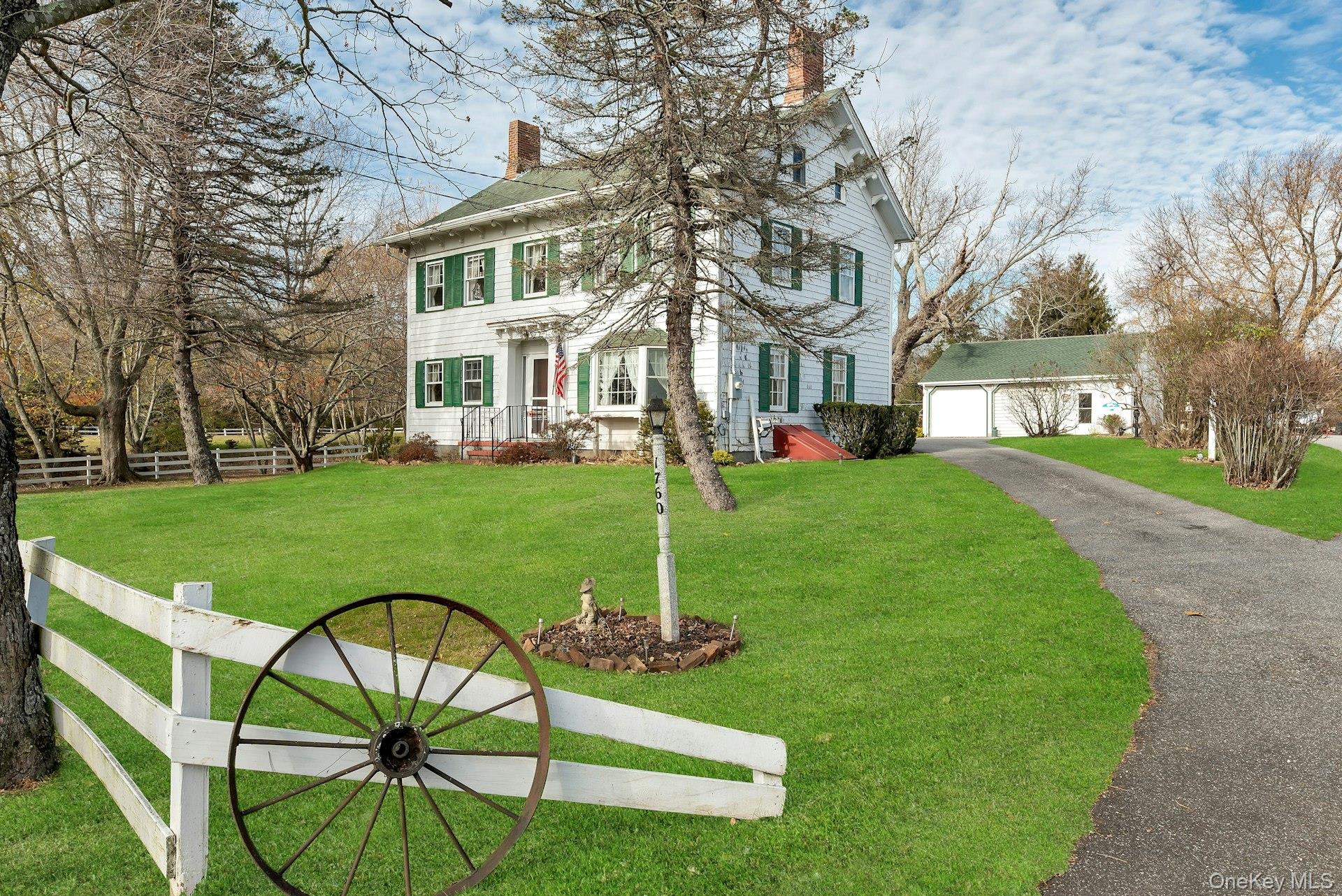 View of front of house with a chimney, asphalt driveway, and an outbuilding