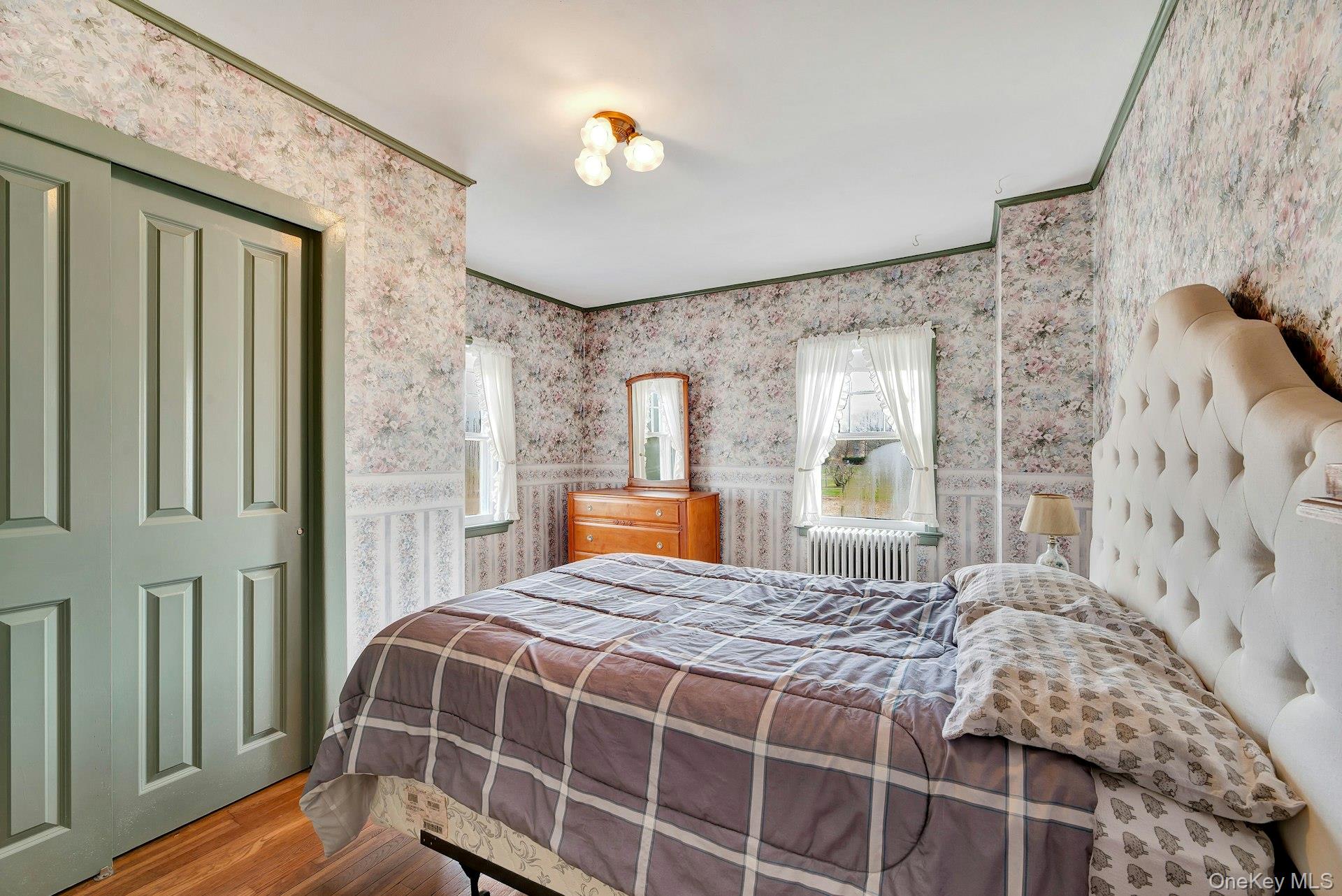 1760 Albertson Lane Greenport, NY 11944 - Photo 16 of 40 Bedroom featuring wood finished floors, wallpapered walls, a closet, and radiator heating unit