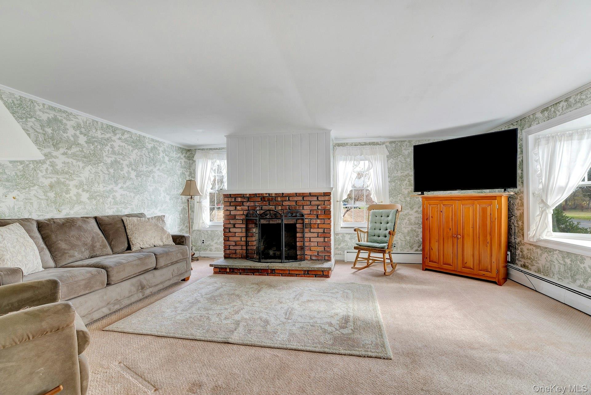 1760 Albertson Lane Greenport, NY 11944 - Photo 4 of 40 Living room featuring wallpapered walls, a fireplace, carpet floors, and a baseboard radiator