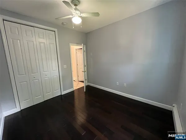 an empty room with wooden floor and fan