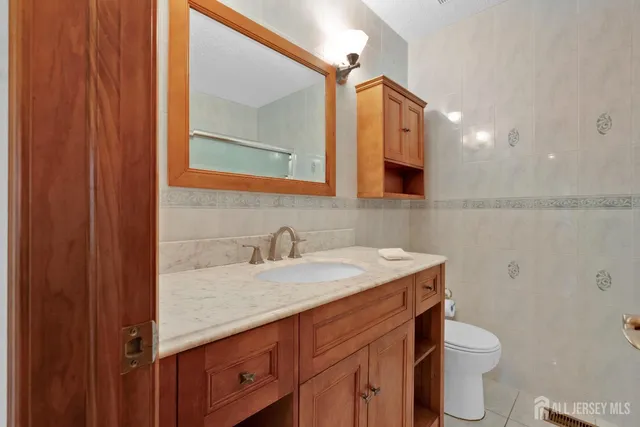 a bathroom with a granite countertop sink toilet and mirror