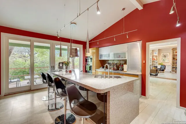 a dining hall with stainless steel appliances kitchen island a table and chairs in it