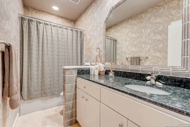 a bathroom with a granite countertop sink and a mirror