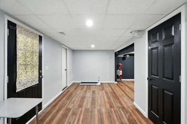 a view of a room with wooden floor fridge and front door