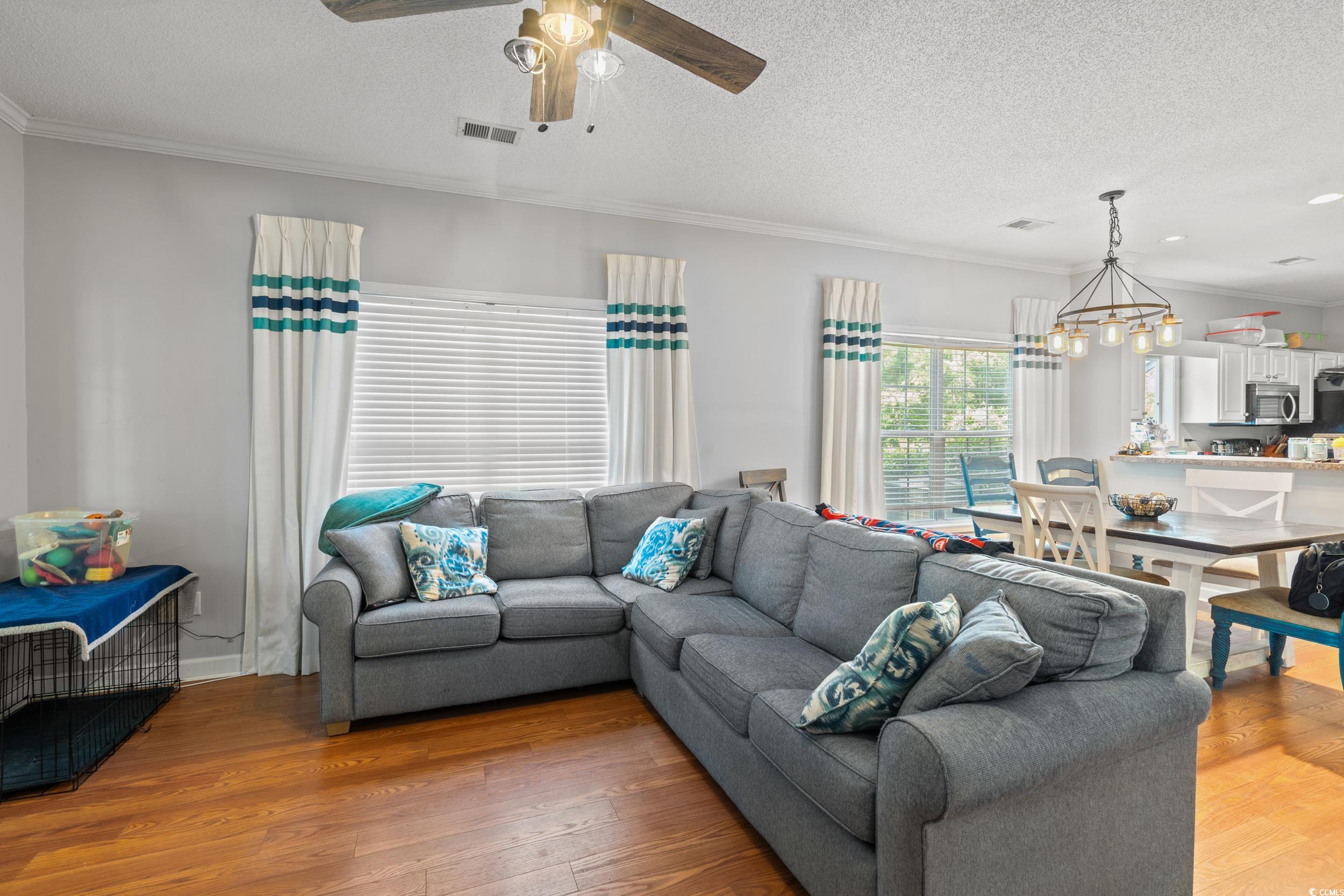 509 Shellbank Drive, Unit B Longs, SC 29568 - Photo 5 of 33 Living room featuring light wood-type flooring, ceiling fan, ornamental molding, a textured ceiling, and a chandelier