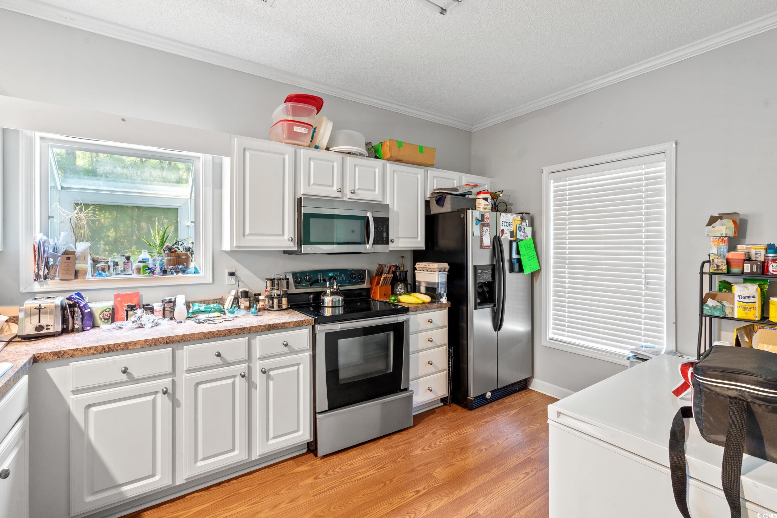 509 Shellbank Drive, Unit B Longs, SC 29568 - Photo 8 of 33 Kitchen featuring stainless steel appliances, ornamental molding, white cabinetry, light wood-style flooring, and light countertops