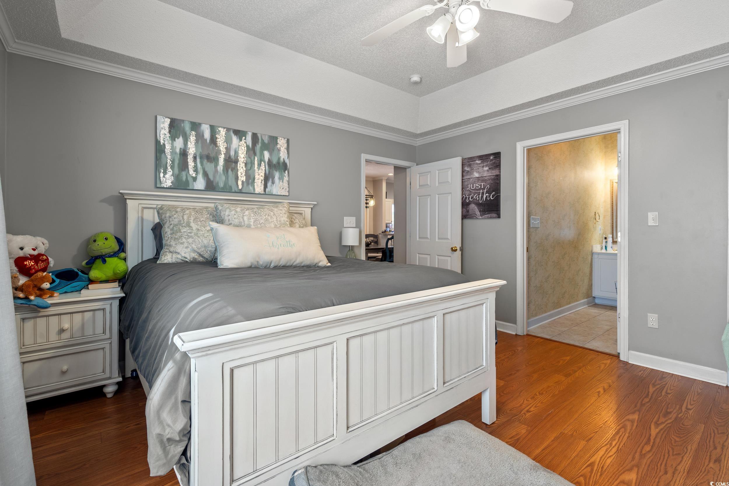 509 Shellbank Drive, Unit B Longs, SC 29568 - Photo 10 of 33 Bedroom featuring wood finished floors, ensuite bathroom, a ceiling fan, a raised ceiling, and ornamental molding