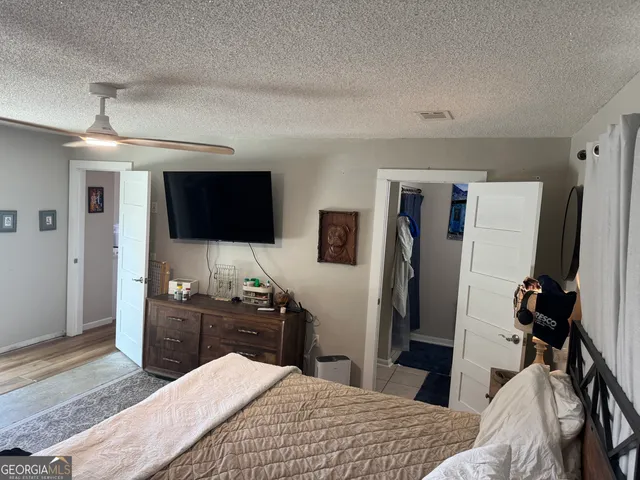 a bedroom with a bed and a flat tv screen on wall