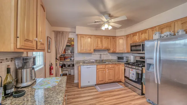 a kitchen with stainless steel appliances granite countertop a refrigerator a stove and a sink