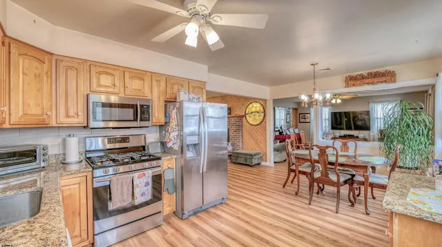 a kitchen with stainless steel appliances kitchen island granite countertop a stove top oven a sink a dining table and chairs with wooden floor