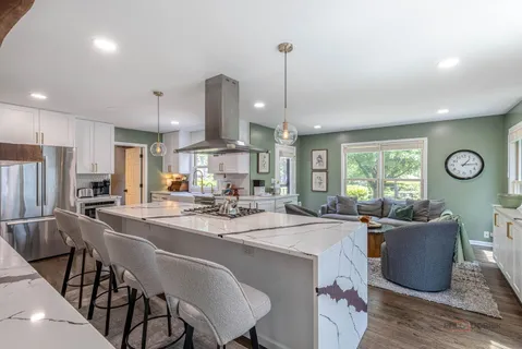 a dining room with stainless steel appliances granite countertop a sink a stove and chairs